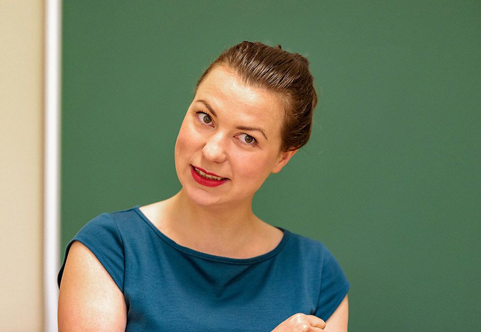 A teacher in a Spanish course at DIE NEUE SCHULE Sprachschule Berlin in front of a green board.
